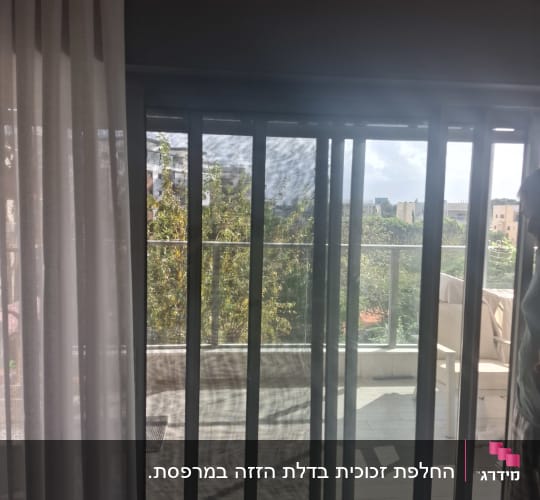 דלת הזזה מזכוכית ביציאה למרפסת עם מעקה זכוכית